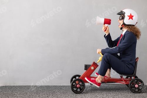Preview: Successfull businesswoman driving toy car outdoor
