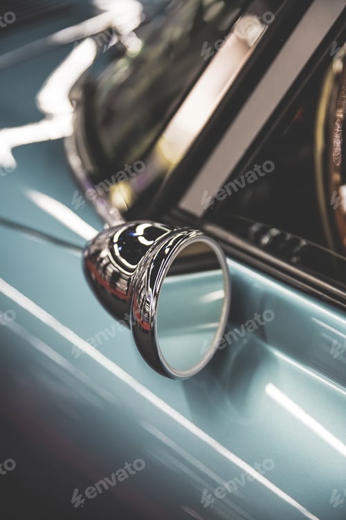 Preview: Vertical shot of an old cars side mirror with a blurred background