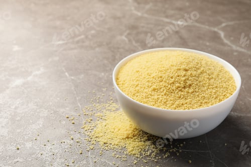 Preview: Bowl with raw couscous on gray background