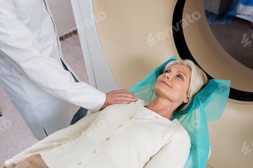 Preview: smiling woman looking at radiologist touching her shoulder before scanning in computed tomography