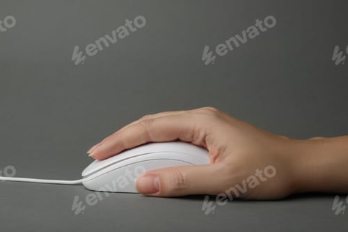 Preview: Woman using wired computer mouse on grey background, closeup
