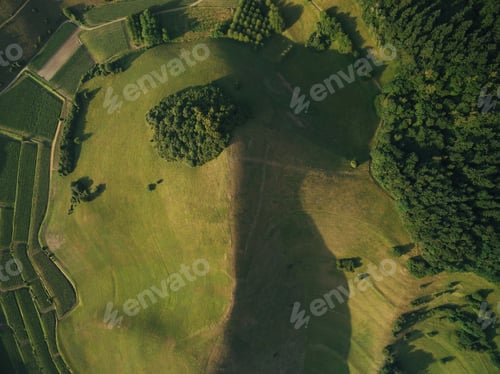 Preview: aerial view of agricultural fields with forest and hill, europe