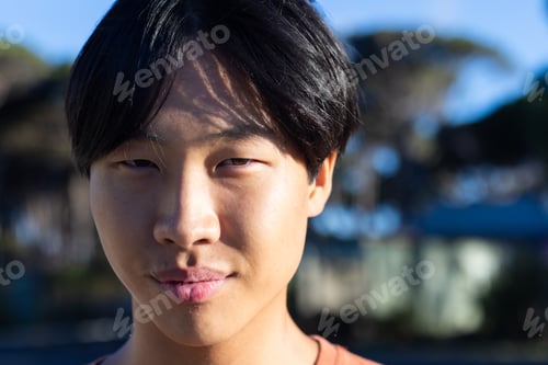 Preview: Asian male student smiling outdoors, enjoying leisure time in natural setting