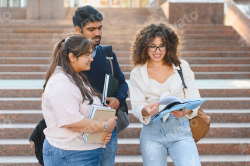 Preview: Diverse students reviewing book studying on campus stairs