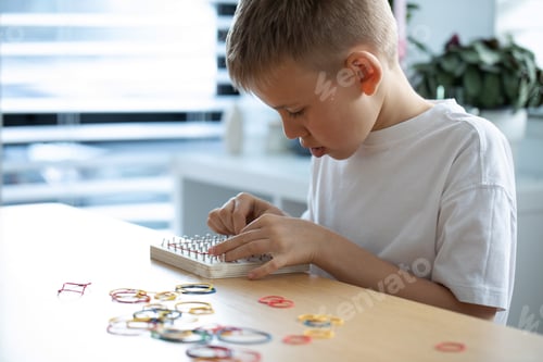 Vista previa: A Child Actively Engaged in a Fun Creative Rubber Band Art Activity Within His Home Environment