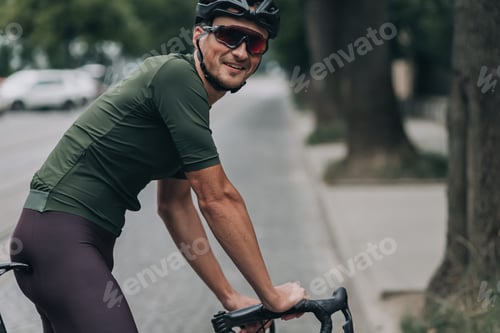 Preview: Man in activewear sitting on bike among empty street
