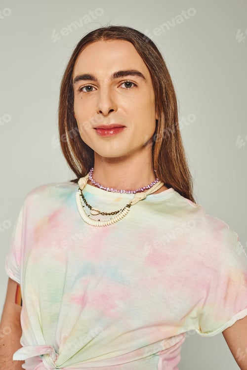 Preview: Portrait of young and long haired homosexual man in tie dye t-shirt looking at camera isolated