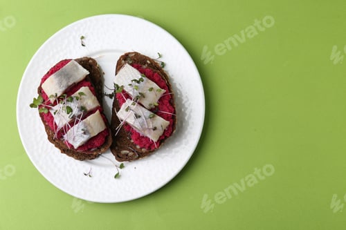 Preview: Tasty sandwiches with herring and horseradish sauce on green background, top view. Space for text