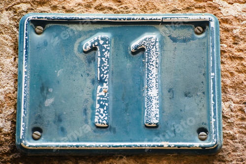Preview: Close up shot of rusty plate with number eleven on old brown wall