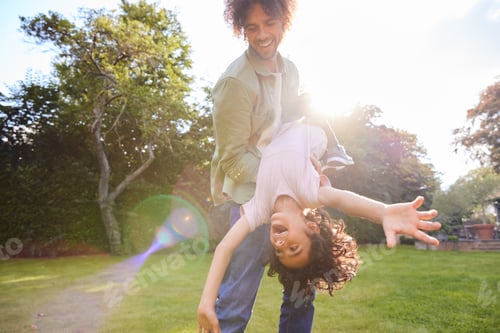 Preview: Father holding son upsidedown in garden