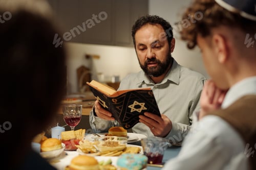 Preview: Focus on bearded rabbi and head of Jewish family reading text from Torah
