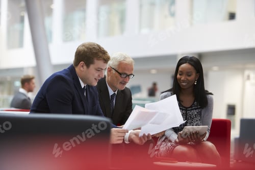 Preview: Businesspeople Discuss Document In Lobby Of Modern Office