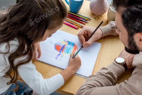 Preview: father and daughter sitting at table and drawing in album