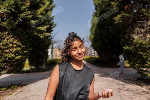 Preview: Young woman enjoying sunny outdoor workout listening to music