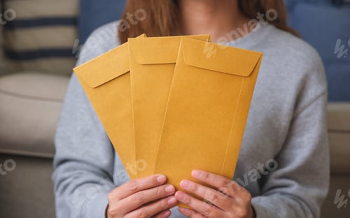 Preview: Closeup image of a woman holding and showing brown envelopes