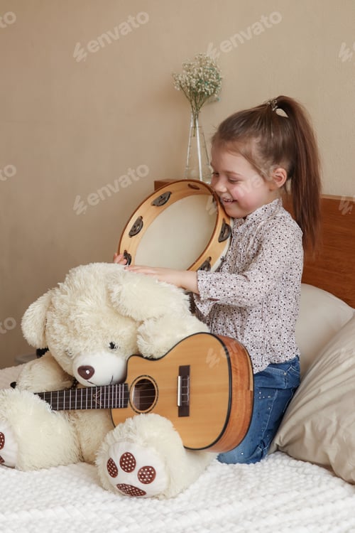 Preview: The girl plays with a teddy bear and musical instruments, depicts a musician from a bear