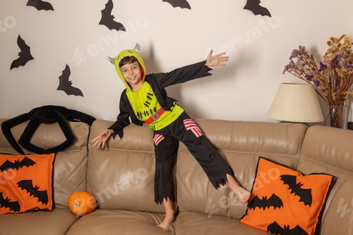 Preview: Child wearing monster costume posing on sofa during halloween party