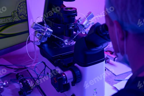 Preview: Man embryologist working with micromanipulator looking at microscope