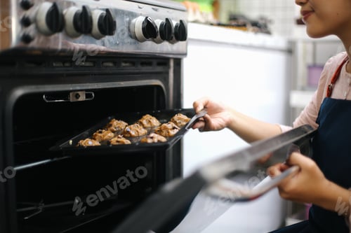 Preview: Cheerful Young Woman Baking Cookies Into oven