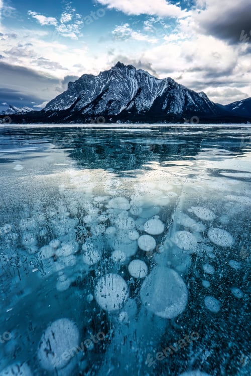 Preview: Frozen Abraham Lake with rocky mountains and natural bubbles frost on winter