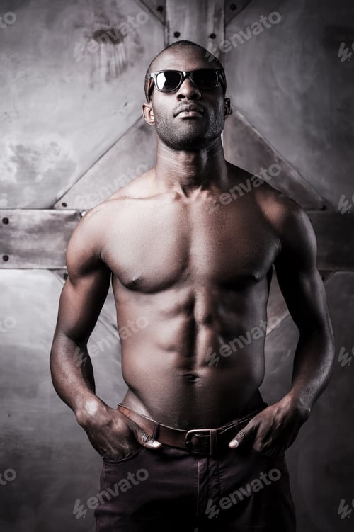 Preview: Confident handsome. Handsome young shirtless African man in sunglasses holding hands in pockets