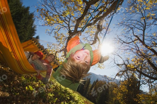 Preview: Austria, Salzburger Land, Altenmarkt, Mother watching son (8-9) playing on swing
