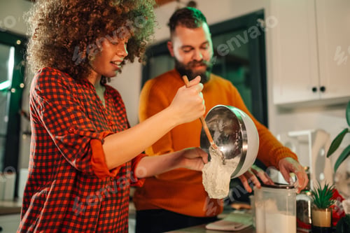 Preview: Couple making dough in kitchen, preparing ingredients for baking