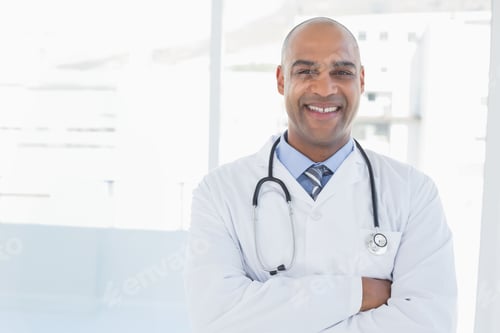 Preview: Male doctor standing in clinic corridor with floor-to-ceiling windows, wearing stethoscope and coat