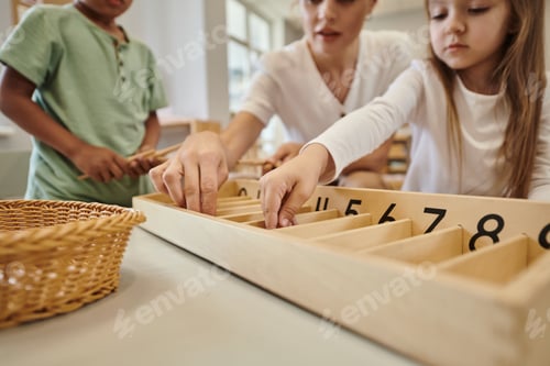 Vista previa: cropped view of teacher taking wooden stick near multiethnic kids in montessori class