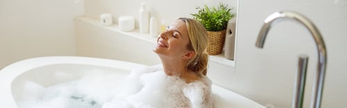 Preview: Happy cheerful pretty female enjoying bubbles and hot water in bathtub. Spa and relax day.