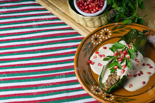 Preview: High angle shot of Chiles en nogada in a plate on a wooden board on the table