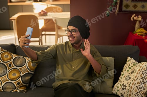 Preview: Waving While Holding Smartphone in Modern Living Room