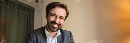 Preview: Smiling mid aged white businessman sitting on a hotel bed