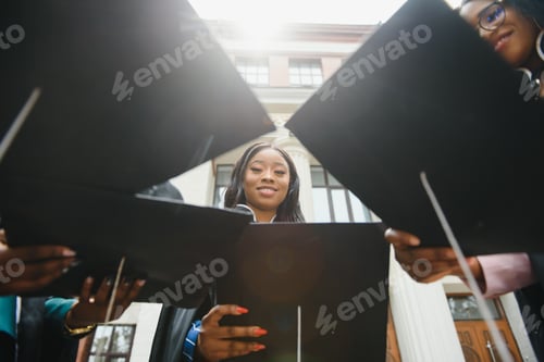 Preview: young graduates standing in front of university building on graduation day