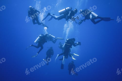Preview: A group of scuba divers descending into infinite blue waters.