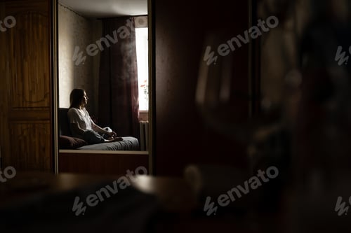 Preview: reflection of a girl in the mirror sitting thoughtfully on the couch