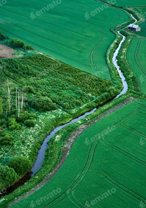 Preview: Aerial view of an idyllic scene featuring a winding river cutting through a lush green field