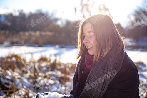 Preview: Happy young woman on a walk in winter with snow in her hands.