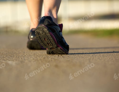 Preview: Rear view of a woman walking in gym shoes on a path