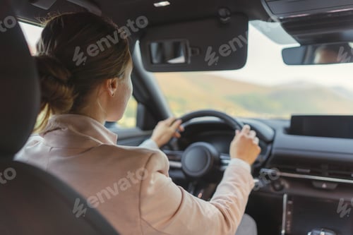 Preview: Rear view of young woman driving her electric car.
