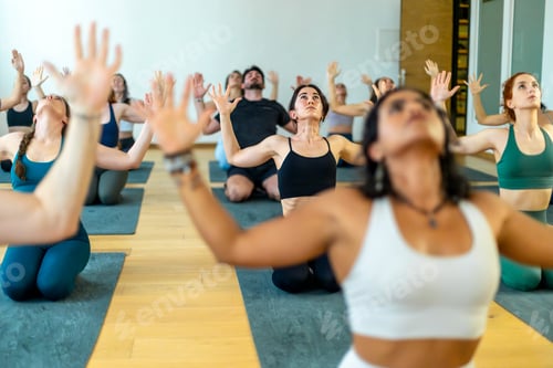 Preview: Diverse group of yoga enthusiasts participate in an expressive arm pose in a studio.