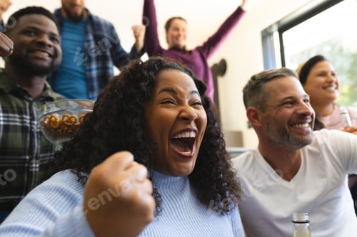 Preview: Excited diverse male and female friends watching sport on tv at home and drinking beers, copy space