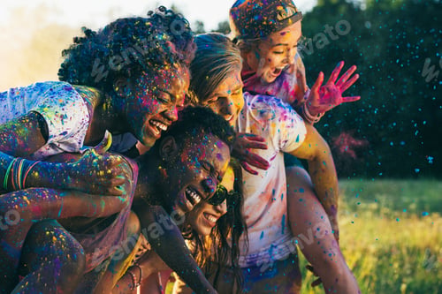 Preview: multicultural happy friends piggybacking together at holi festival