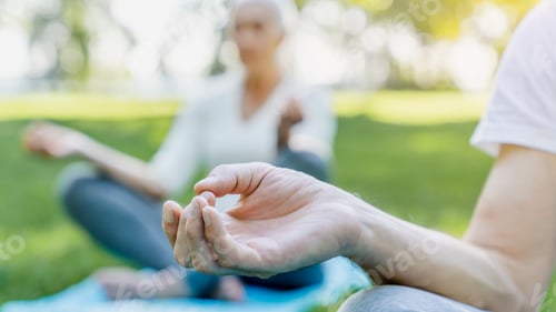 Preview: Yoga at park. Close up shot of senior couple sitting in lotus pose on green grass in meditation