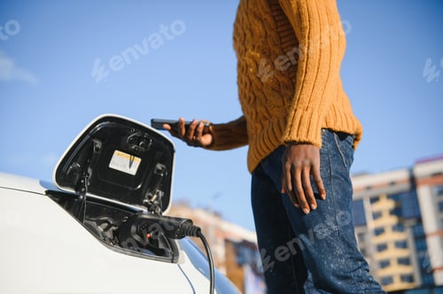 Preview: African American man charging his electric car.