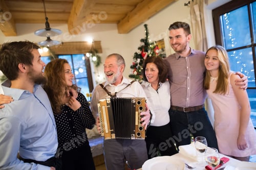 Preview: Senior man playing accordion for happy family at Christmas