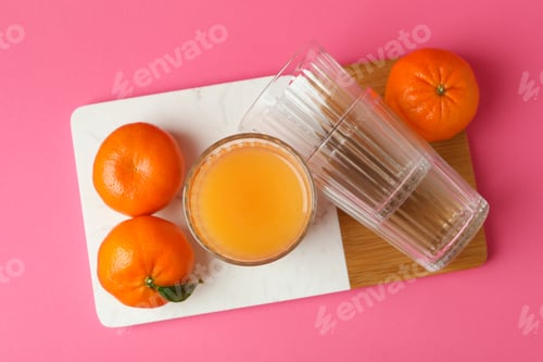 Preview: Board with mandarin juice and ingredients on pink background