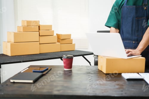 Preview: A man is working at his desk, preparing parcel boxes for shipment. He checks packs items carefully