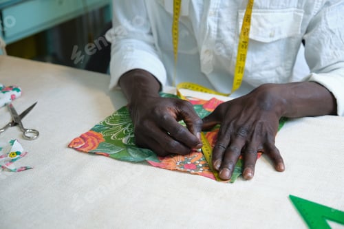 Preview: Unrecognizable tailor measuring fabric using a measure tape.