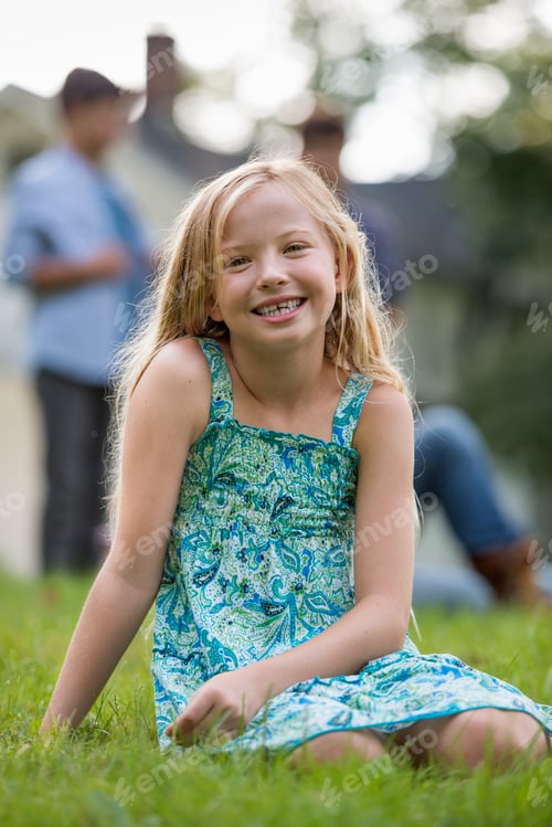 Visualização: Uma criança sentada na grama em uma festa de verão.